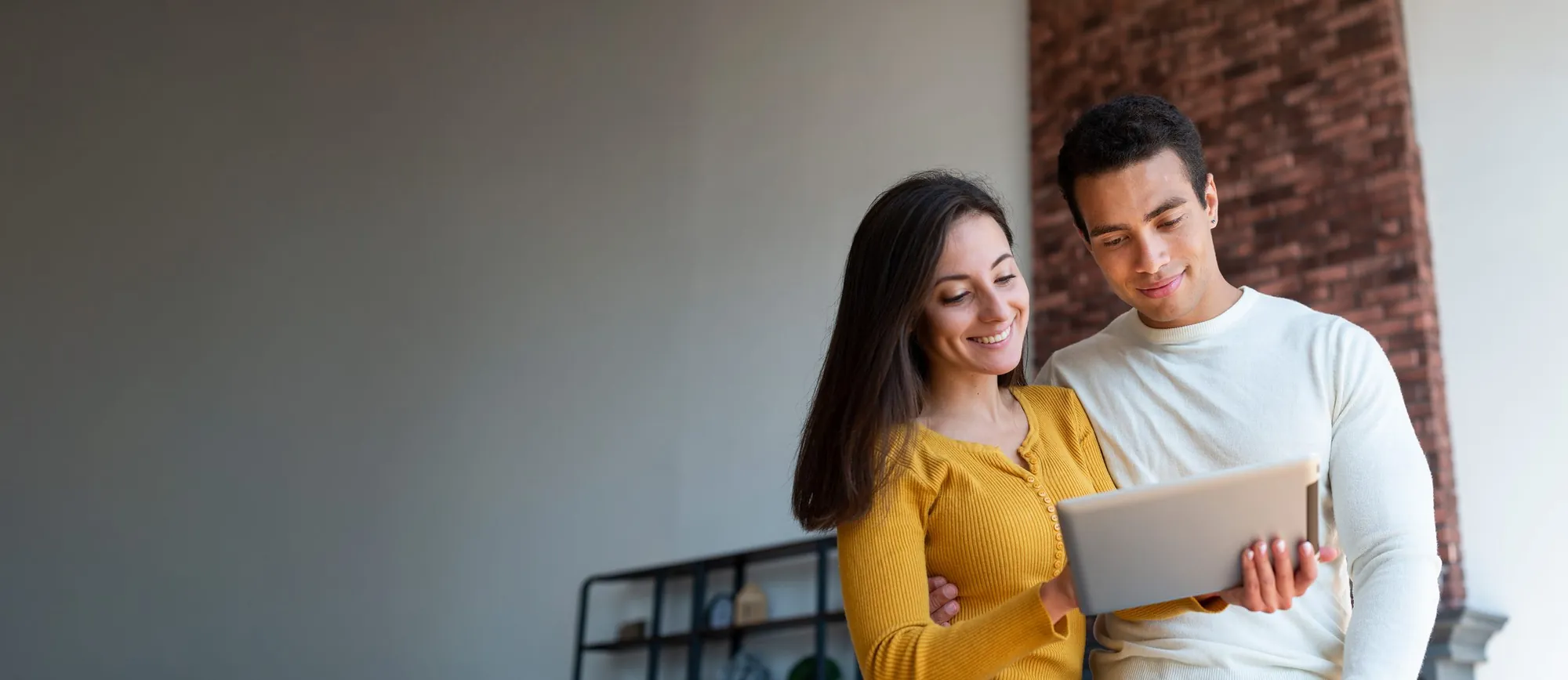 Pareja sonriente revisando una tableta en casa