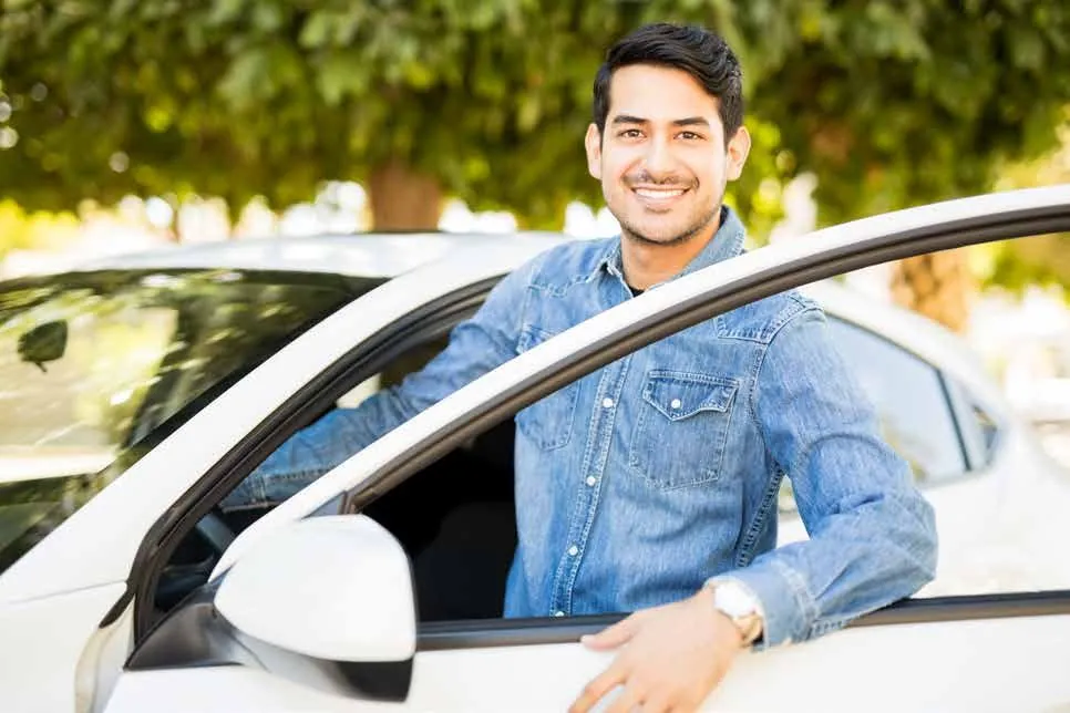 Joven sonriente junto a su vehículo