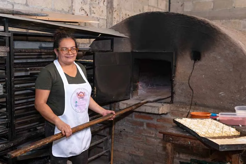 Panadera sacando pan del horno en su empresa